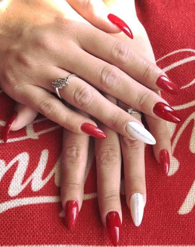 Smalto rosso lucido con un'unghia glitterata argento